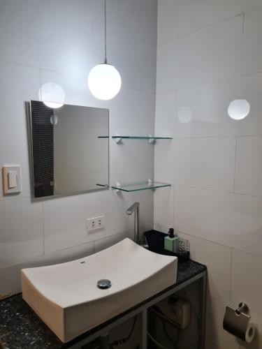 ein Badezimmer mit einem weißen Waschbecken und einem Spiegel in der Unterkunft Huge condo unit near Burgos Circle, St Lukes, Shangri-La - P Hamptons T1 in Manila