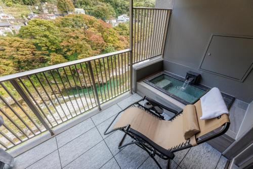 balcone con sedia e vasca da bagno. di Minakami Onsen Aratashi Minakami a Minakami