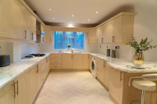 a large kitchen with wooden cabinets and a window at Solihull 5 Bed Home near NEC/Bham airport/JLR/HS2 in Solihull