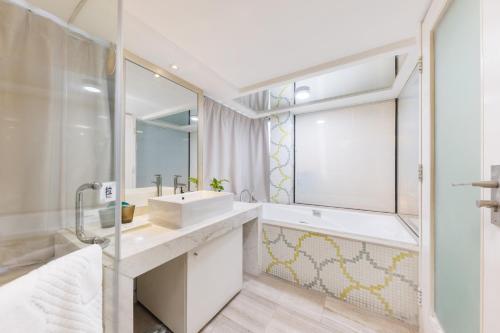La salle de bains blanche est pourvue d'un lavabo et d'un miroir. dans l'établissement Sunflower Hotel & Residence, Shenzhen, à Shenzhen