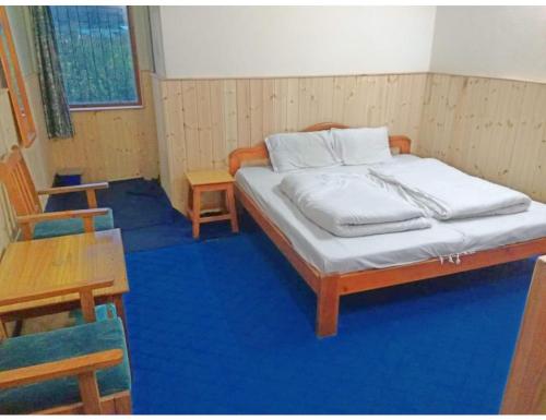 a bedroom with a bed and a table and chairs at Mini Swiss, Harshil in Harsil