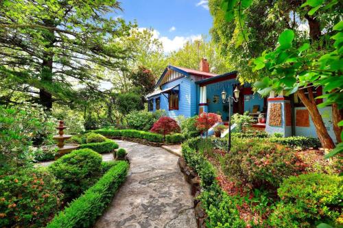 a blue house with a garden in front of it at KUBBA ROONGA GUESTHOUSE - Boutique Luxury Spa Retreat & Gardens - Blue Mountains in Blackheath