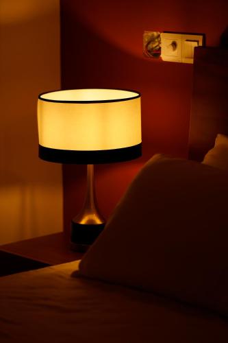 a lamp sitting on a table next to a bed at The Greens Luxury Boutique Villa in Karagampitiya