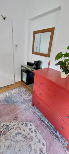 a living room with a red dresser and a table at Süßes Gästehäuschen in 1A Lage in Bochum