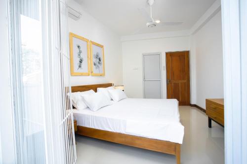 a white bedroom with a bed and a window at The Greens Luxury Boutique Villa in Karagampitiya