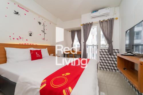 a bedroom with a bed with a red blanket on it at RedLiving Apartemen Grand Sentraland - Bangde Rooms in Karawang