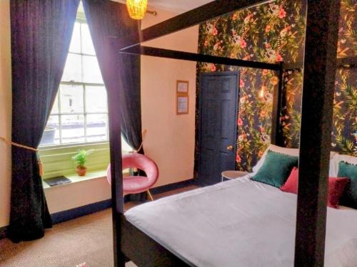 ein Schlafzimmer mit einem Himmelbett und einem Fenster in der Unterkunft Chestnut Bed and Breakfast in Bourton on the Water