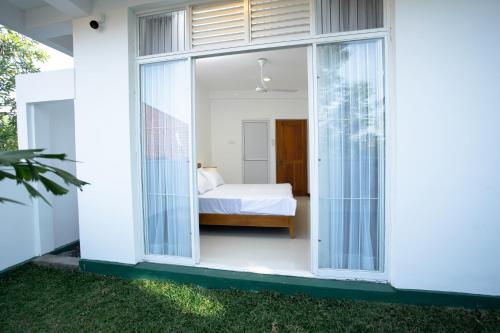 a bedroom with a bed in a white house at The Greens Luxury Boutique Villa in Karagampitiya