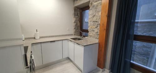 uma cozinha com armários brancos, um lavatório e uma janela em APARTAMENTO EN EL CASCO HISTÓRICO DE PLENTZIA II em Plencia