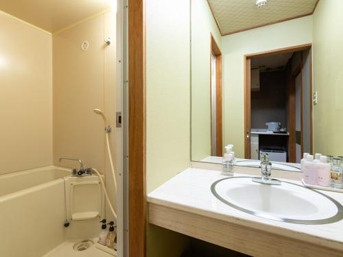 a bathroom with a sink and a tub and a mirror at Fukujyuso in Shima