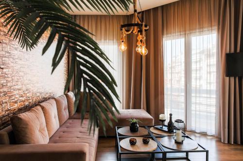 a living room with a couch and a palm tree at Superior One Luxury Apartments in Thessaloniki