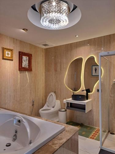 a bathroom with a tub and a toilet and a chandelier at Casapapa Home&Space in Talat Amphoe Nakhon Chai Si