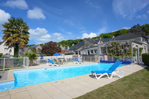 une piscine avec des chaises bleues et une maison dans l'établissement Appart Hôtel de la baie, à Saint-Jean-le-Thomas