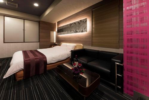 a hotel room with a bed and a couch at HOTEL ESTASI Adult only in Wakayama