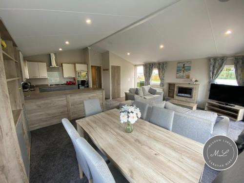 Il dispose d'une cuisine et d'un salon avec une table et des chaises en bois. dans l'établissement The Retreat 1 - Hot tub Lodge, pet friendly, WiFi & bed linen- Golden Palm Resort - Meadow Lakes Caravan & Lodge Hire, à Chapel St. Leonards