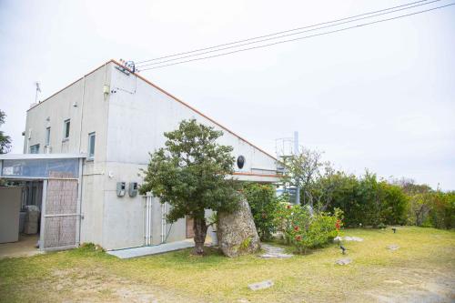 a building with a tree in front of it at 古宇利ゲストハウス1835 in Kouri