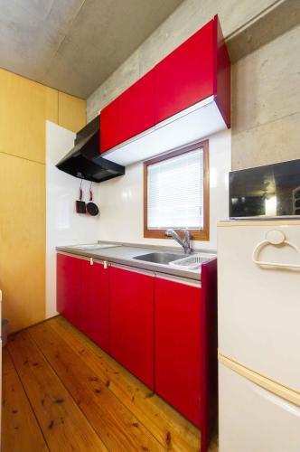 a kitchen with red cabinets and a sink at 古宇利ゲストハウス1835 in Kouri
