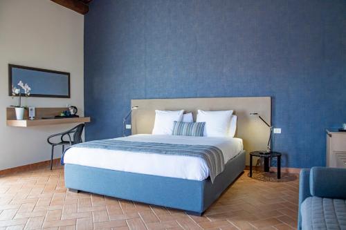 1 dormitorio con 1 cama con pared azul en Feudogrande Bio Relais Hotel, en Fiumefreddo di Sicilia