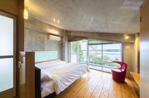 a bedroom with a bed and a large window at 古宇利ゲストハウス1835 in Kouri