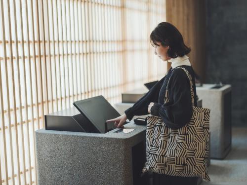 a woman standing at a desk with a laptop computer at SOKI Kanazawa in Kanazawa