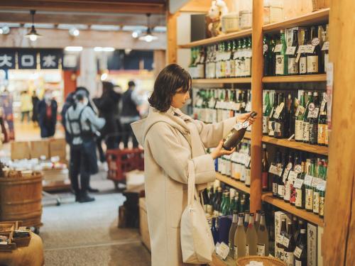 a woman standing in a store looking at a bottle of wine at SOKI Kanazawa in Kanazawa