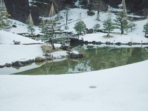 a garden in the snow with a bridge at SOKI Kanazawa in Kanazawa
