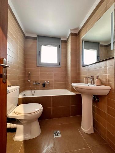 a bathroom with a toilet and a tub and a sink at EVa's Luxury Apartments No 2 in Áyios Spirídhon