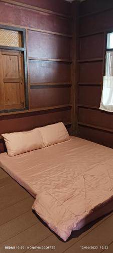 uma cama num quarto com uma parede de madeira em Chanmuang guesthouse em Mae Hong Son