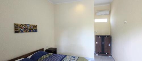 a bedroom with a bed and a painting on the wall at Jero Harum Homestay in Krambitan