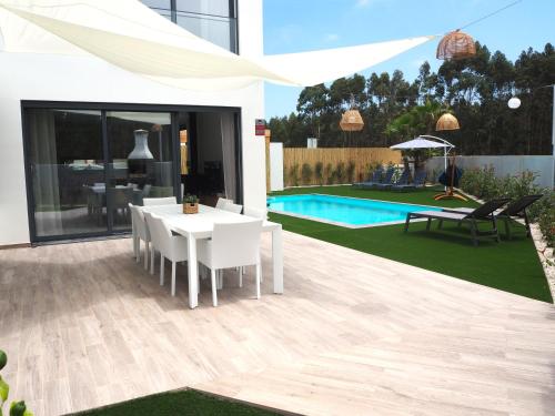 a patio with a white table and chairs and a pool at Villa Au Bain Marie in São Martinho do Porto