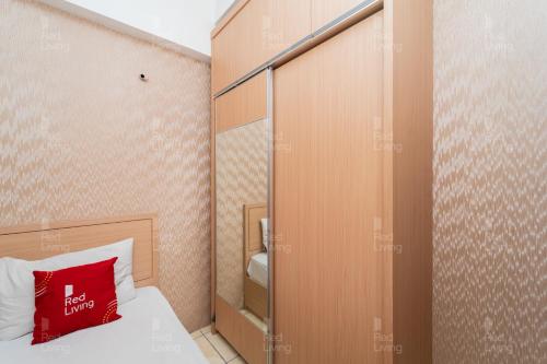 um pequeno quarto com uma cama com uma almofada vermelha em RedLiving Apartemen Tamansari Panoramic - Rasya Room with Netflix em Bandung