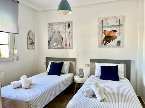 2 Betten in einem Zimmer mit blauer und weißer Bettwäsche in der Unterkunft Rey Don Jaime in Benidorm