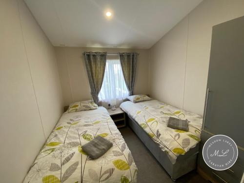 deux lits dans une petite pièce avec une fenêtre dans l'établissement The Retreat 1 - Hot tub Lodge, pet friendly, WiFi & bed linen- Golden Palm Resort - Meadow Lakes Caravan & Lodge Hire, à Chapel St. Leonards