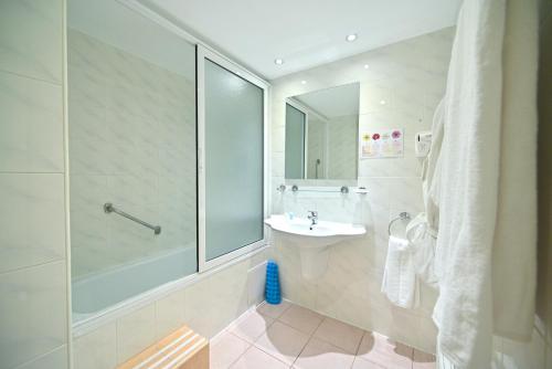 baño blanco con ducha y lavamanos en Europe Hotel, en Ereván