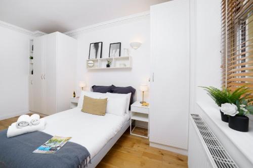 um pequeno quarto branco com uma cama e uma janela em 2 Bedr, 3 Beds, 1 Bath Thames, Trafalgar SQ em Londres