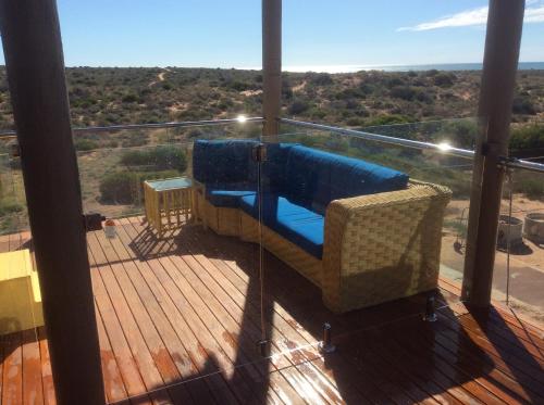 a balcony with a blue couch on a deck at On the Deck @ Shark Bay in Denham