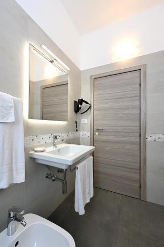 un bagno con lavandino, WC e specchio di Hotel Italia a Monfalcone