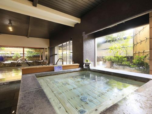 諏訪市にある信州上諏訪温泉 浜の湯の大きな窓付きの客室内の大きなスイミングプールを提供しています。