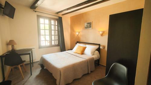 a bedroom with a bed and a desk and a window at Auberge Saint Jacques in Conques