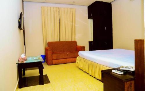 a bedroom with a bed and a chair and a table at Royal Living Hotel & Suites in Chittagong