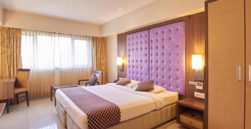 a bedroom with a large bed and a purple headboard at Hotel Corporate in Navi Mumbai