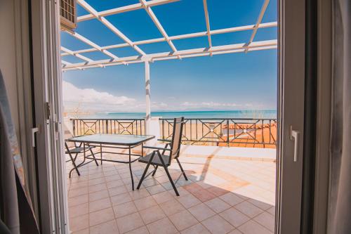 balcón con mesa, sillas y vistas al océano en Villa Olga Sea Front Katakolo - Happy Rentals, en Katakolon