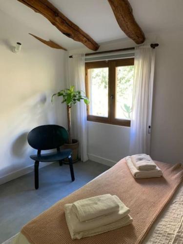 a bedroom with a bed and a chair and a window at Casa Valleta in Tivenys