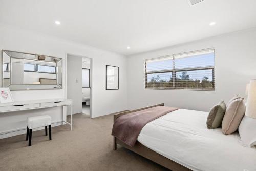 a bedroom with a bed and a desk and a mirror at Modern Minimalistic Home 3BR in Perth