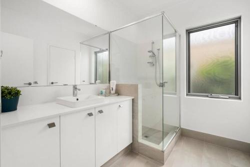 y baño blanco con lavabo y ducha. en Modern Minimalistic Home 3BR, en Perth