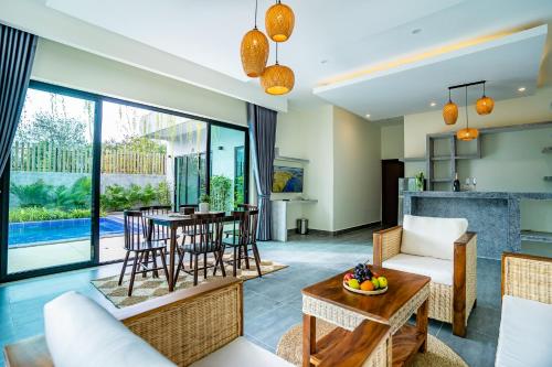 uma sala de estar em plano aberto com uma mesa e cadeiras e uma sala de jantar em Rainforest Hotel by NSUN em Kampot