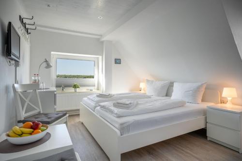 a white bedroom with a bed and a bowl of fruit on a table at Deichhus Nordseeliebe direkt am Deich - Nordsee - Dagebüll - Am Vogelreservat in Dagebüll