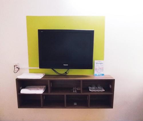 a television on a shelf with a green wall at Nhà nghỉ Thiện Trang in Kiến An