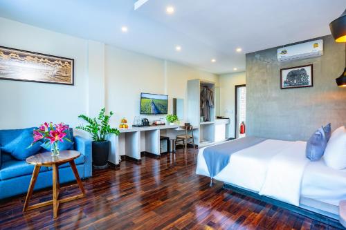 a hotel room with a bed and a blue couch at Rainforest Hotel by NSUN in Kampot
