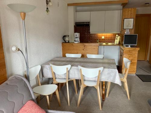 uma cozinha com uma mesa e cadeiras brancas e uma mesa e uma cozinha em Apartment Grand Vallon em Grimentz